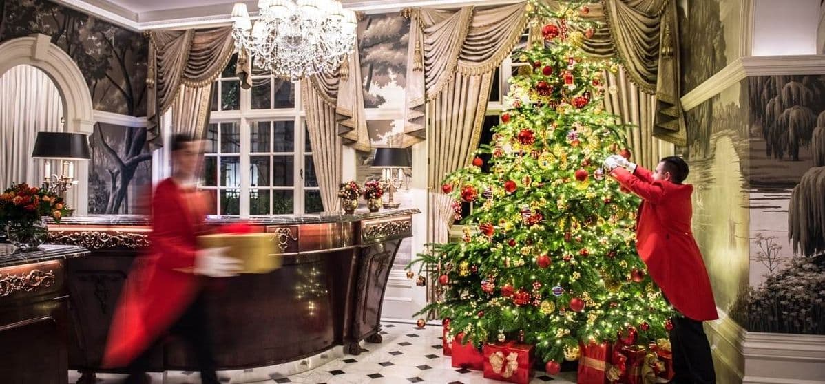 People decorating a large tree in an ornate room